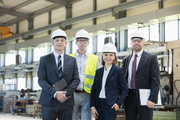 Fototapeta premium Portrait of confident business people wearing hardhats in metal industry