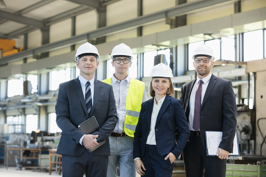 Portrait of confident business people wearing hardhats in metal industry