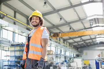 Portrait of smiling young manual worker standing in factory