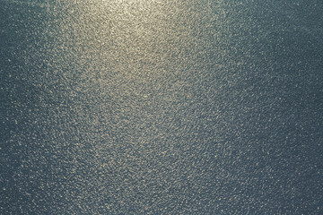 Brushed ice on the water surface and shines in the light. Focus point in the center. Background.