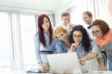 Group of businesspeople using laptop at desk in creative office