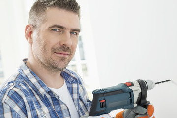 Portrait of mid-adult man drilling hole in wall