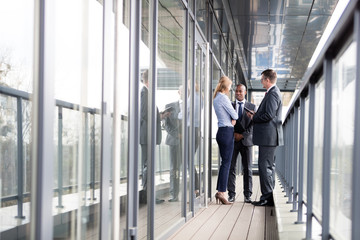 Full length of multi-ethnic business people discussing on office balcony