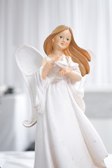 Little figure of a Christmas angel with little bird isolated on white curtain background