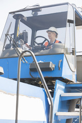 Female worker operating forklift truck in shipping yard