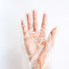Hand wearing Transparent Disposable Plastic Glove on white Background