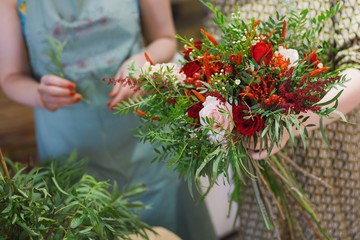 Florist at work. Two females making bouquet of red flowers