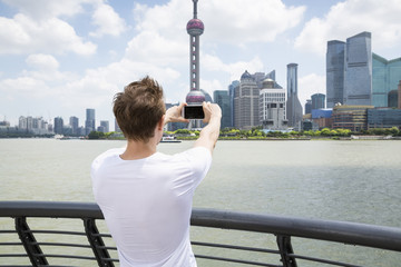 Fototapeta premium Rear view of man photographing Oriental Pearl Tower while standing by railing