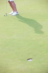 Low section of middle-aged man playing golf at course