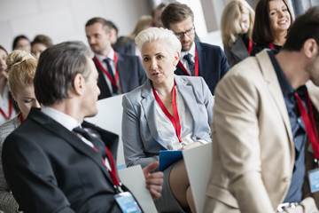 Businessman talking to businesswoman in seminar hall at convention center