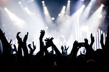 silhouettes of hands on concert in front of bright stage lights
