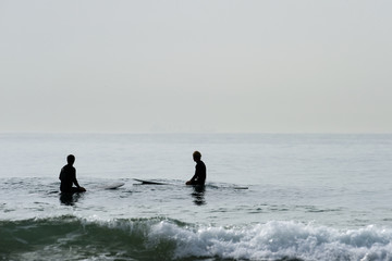 Brothers sitting in the ocean waiting for waves