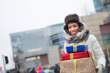 Happy woman looking away while carrying stacked gifts during winter