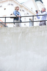 Low angle view of man photographing woman by railing outside church