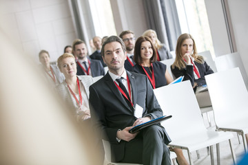 Businessman looking at public speaker during seminar in convention center