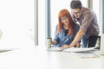 Businesspeople analyzing file together at desk in creative office