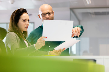 Businesswoman with male colleague discussing over documents in office