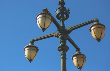 Fototapeta na wymiar Old vintage street light with four arms on green cast iron poll