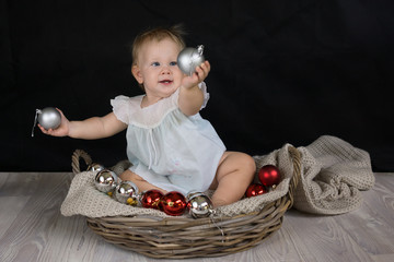 Baby girl playing with Christmas balls and giving one to someone
