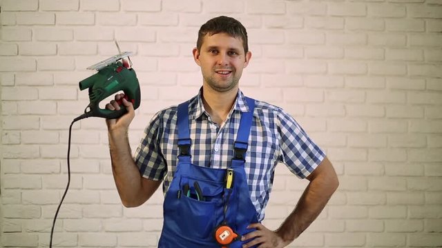 Man with an electric jigsaw.  Work carpenter with an electric tool. Man holds in his hand an electric jigsaw.
