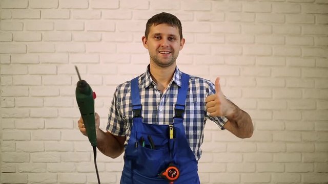 A man with a perforator.  The man with the drill on the brick wall background. Working, hammer, drill.  Master builder, repairman tool. 