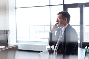 Side view of mature businessman talking on mobile phone at office