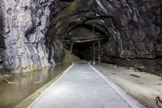 Abandoned old mine ore tunnel with rails and white lime