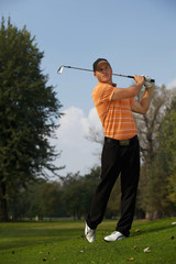 Young man swinging golf club