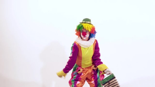 Funny female clown having fun while dancing actively holding harmonica