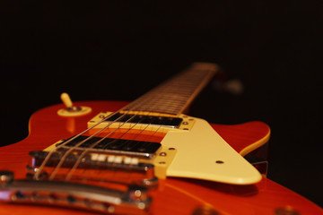 Vintage electric guitar closeup on the black background. Selective focus.