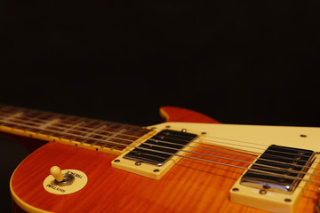 Honey sunburst vintage electric rock guitar closeup on the black background, with plenty of copy...