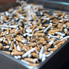 Large ashtray full of different cigarette butts, smoking at least