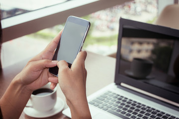 Close Up of woman hands using mobile phone and laptop computer with blank copy space screen for your advertising text message or content business in the Vintage effect.