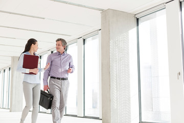 Businessman and businesswoman talking while walking in new office