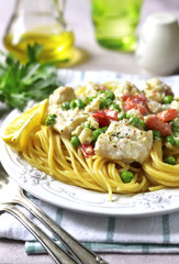 Codfish in a cream sauce with vegetables garnished with spaghett