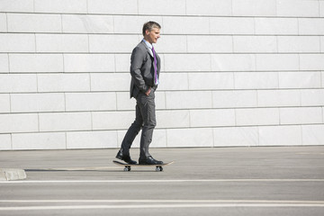 Fototapeta na wymiar Businessman skateboarding on street
