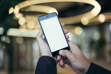 Close-up of a smartphone with a blank screen in male hands. Male finger on the button of gadget....