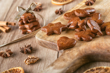 gingerbread on board with baking ingredients like cinnamon, orange slices and star anise, christmas background