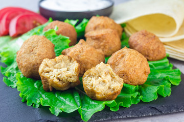 Chickpea falafel balls on slate board with vegetables and sauce