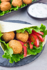 Chickpea falafel balls with vegetables and sauce, roll sandwich preparation, vertical