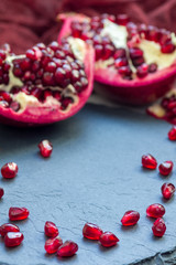 Fresh peeled red ripe pomegranate on gray slate board, vertical, copy space
