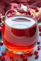 Pomegranate drink in glass and fruit on background, closeup, vertical