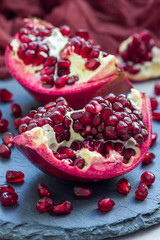 Fresh peeled red ripe pomegranate on gray slate board, vertical