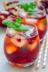 Mojito cocktail with pomegranate, mint, lemon juice and ice in glass, vertical
