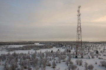 Telecommunications tower and satellite dish telecom network on evening sky with sundown and winter...