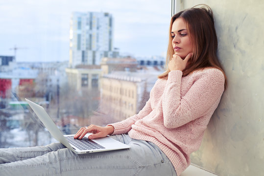 Girl in pensive mood looking at the screen of a laptop and scrat
