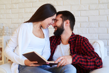 Lovesome couple touching foreheads and noses sitting in an armch