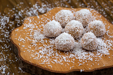 Fototapeta na wymiar Sweet chocolate balls in coconut flakes on wood background