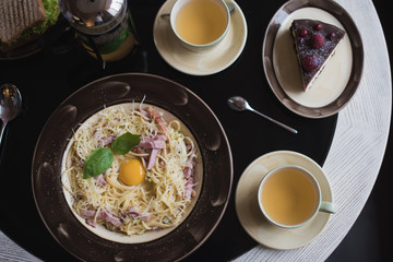 Classic Pasta carbonara  with bacon and egg yolk, egg and Parmesan with two cups of tea and desserts.