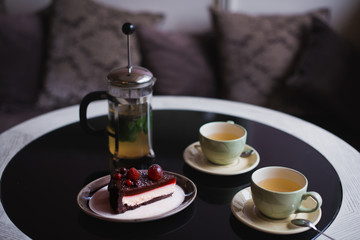 Piece of chocolate cake with cup of tee and fresh berry on black background